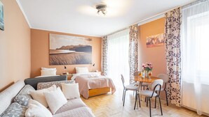 Una habitación acogedora con cama, sofá, mesa de comedor y sillas, y un cuadro en la pared.