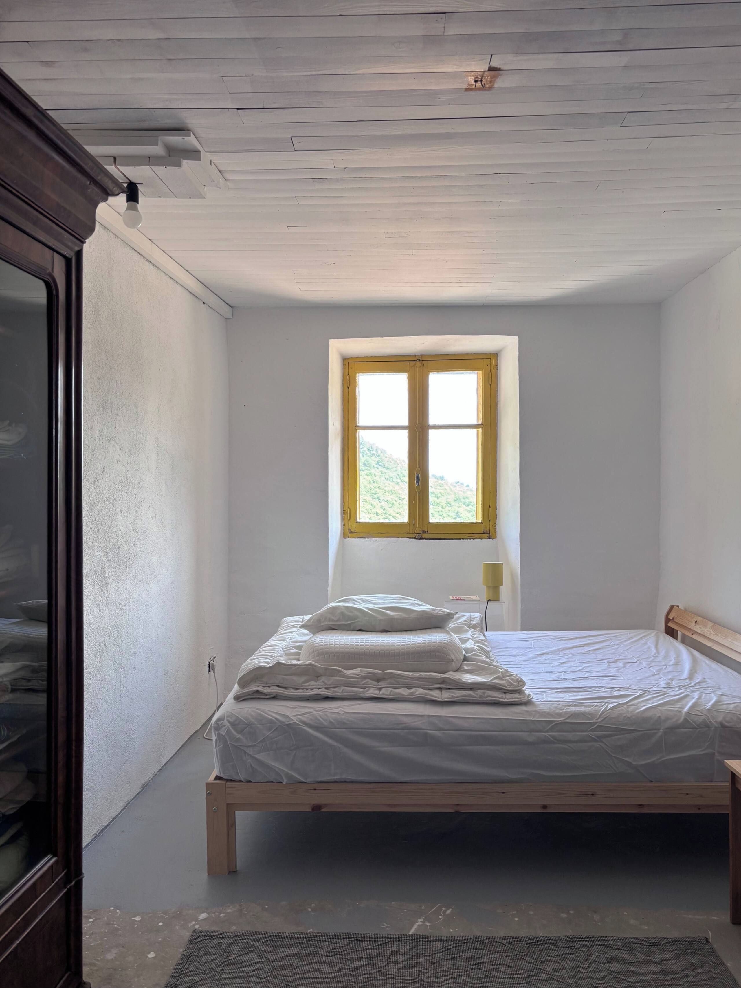 Una camera con un letto singolo, una finestra e una porta.