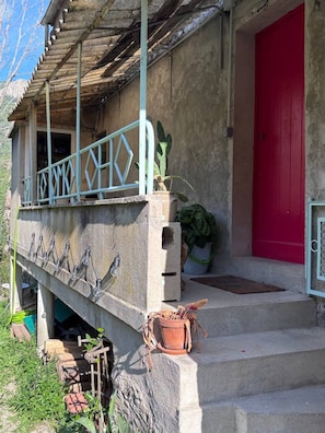 A concrete structure with a metal railing, a red door, and a potted plant. - Ardèche - Unique home in the Bésorgues Valley. (Freyssenet Labastide-sur-Bésorgues)