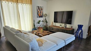 Ein modernes Wohnzimmer mit einer Couch, einem Couchtisch, einem Fernseher und Dekorationselementen.