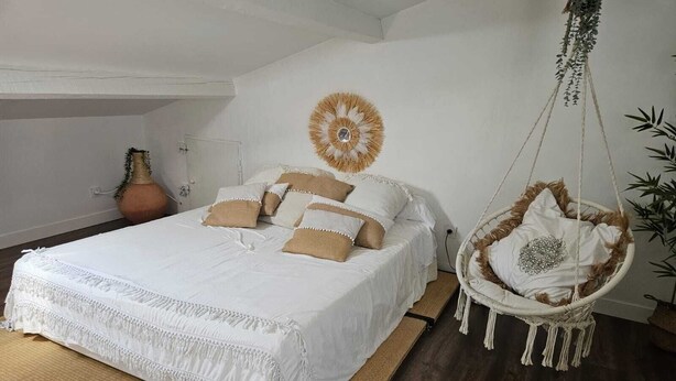 Ein Schlafzimmer mit einem großen Bett, einem Hängekorbsessel und einem Wanddekor.