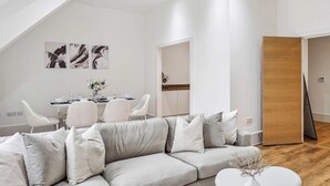 Een moderne woonkamer met een hoekbank, een eettafel met stoelen en een houten deur.