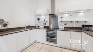 Een moderne keuken met witte kasten, roestvrijstalen apparatuur en een centraal eiland.