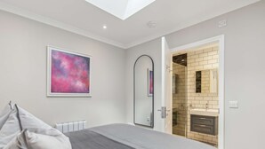 Una camera da letto con un letto, un termosifone, un quadro e un bagno visibile tramite una porta aperta.