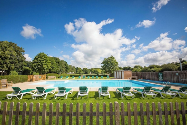 Une piscine avec des chaises longues et une clôture en bois au premier plan.