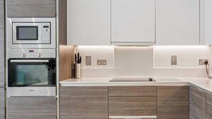 A modern kitchen with built-in appliances, a central island, and wooden cabinetry. - Lavender House - Luxury 4-Bed Home with Parking - New for Spring 2026! (Maidenhead)