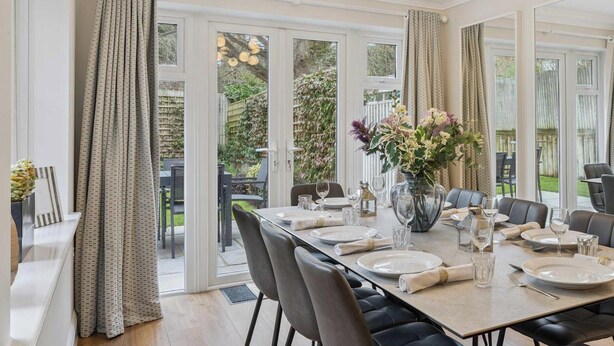 A dining room with a large table set for six, surrounded by black upholstered chairs. - Lavender House - Luxury 4-Bed Home with Parking - New for Spring 2026! (Maidenhead)