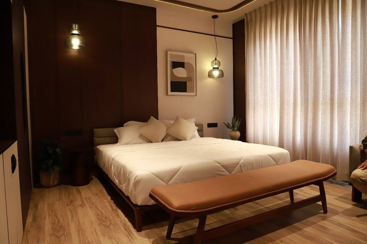 A modern bedroom with a large bed, a bench, and two pendant lights.