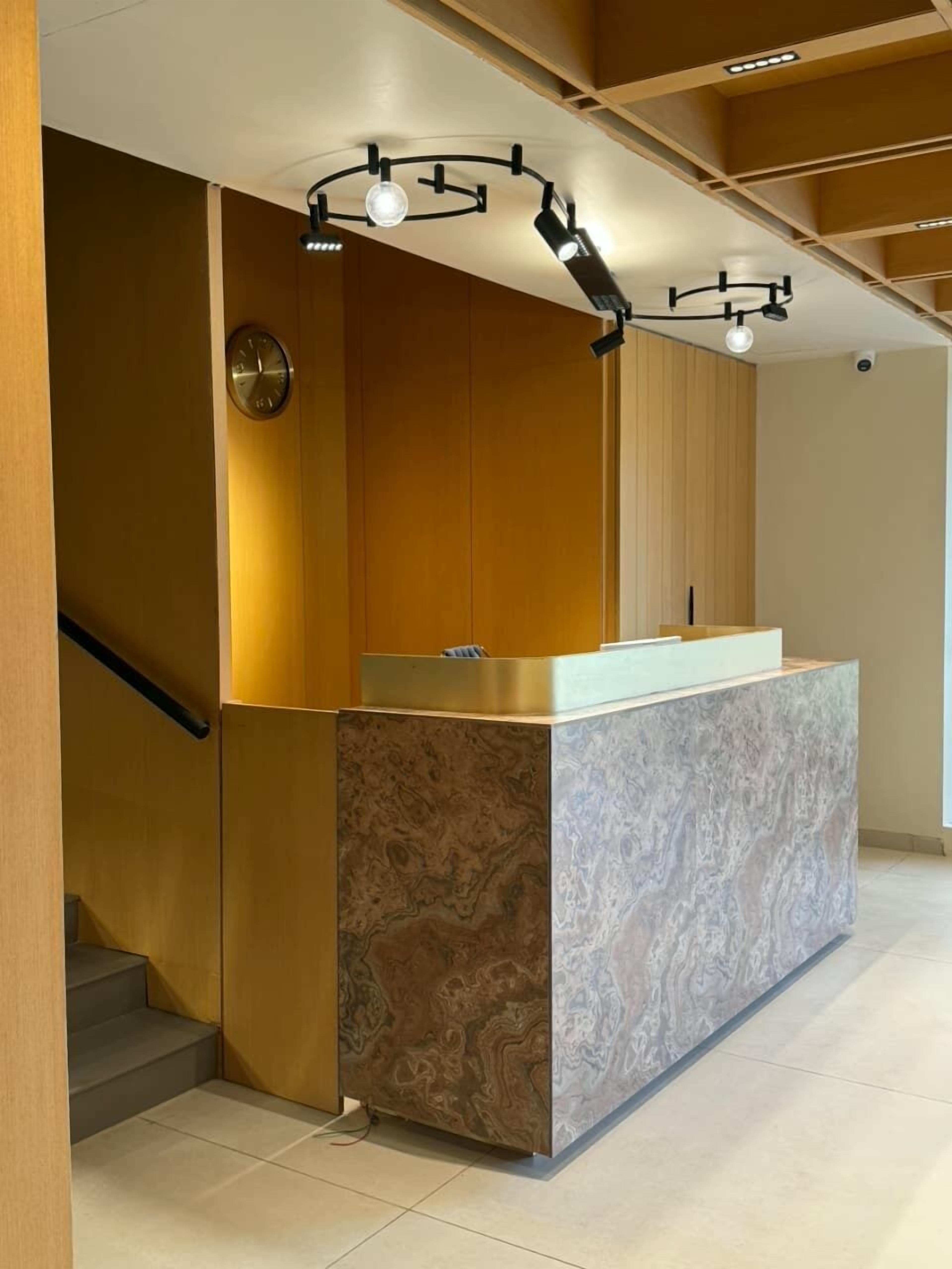 En moderne reception med en marmordisk, træpaneler og en trappe.