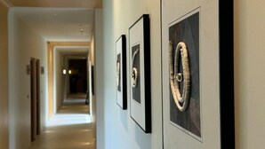 A hallway with framed artwork on the wall, leading to a room with a door at the end.