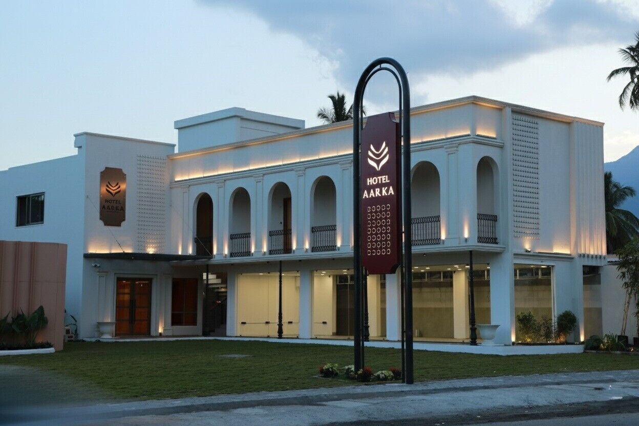 A modern hotel with a white facade, arched balconies, and a prominent entrance.