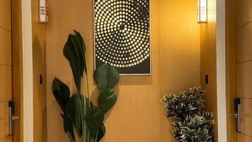 A hallway with a wooden wall, a large abstract art piece, and two potted plants.