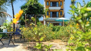 A two-story building with balconies, surrounded by greenery and a garden with yellow flowers. - Calm House 4 Hoi An (Thanh pho Hoi An)