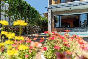 A modern house with a swimming pool, a balcony, and a garden with flowers.