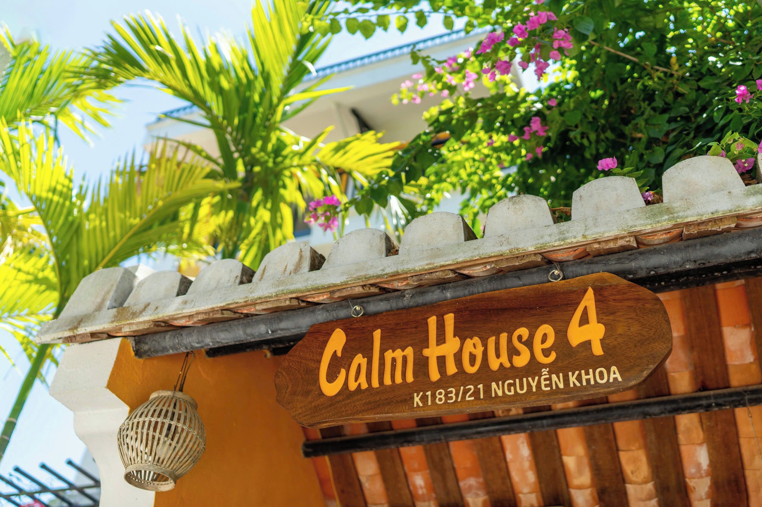 Une pancarte en bois indiquant « Calm House 4 » et une adresse.