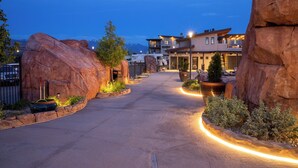 Un hotel moderno con un patio central, grandes formaciones rocosas y una vista de montaña al fondo.