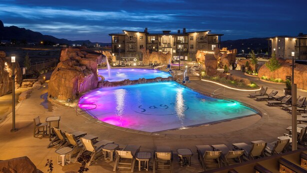 Un resort con una piscina grande, sillas de descanso y un edificio con varios balcones.