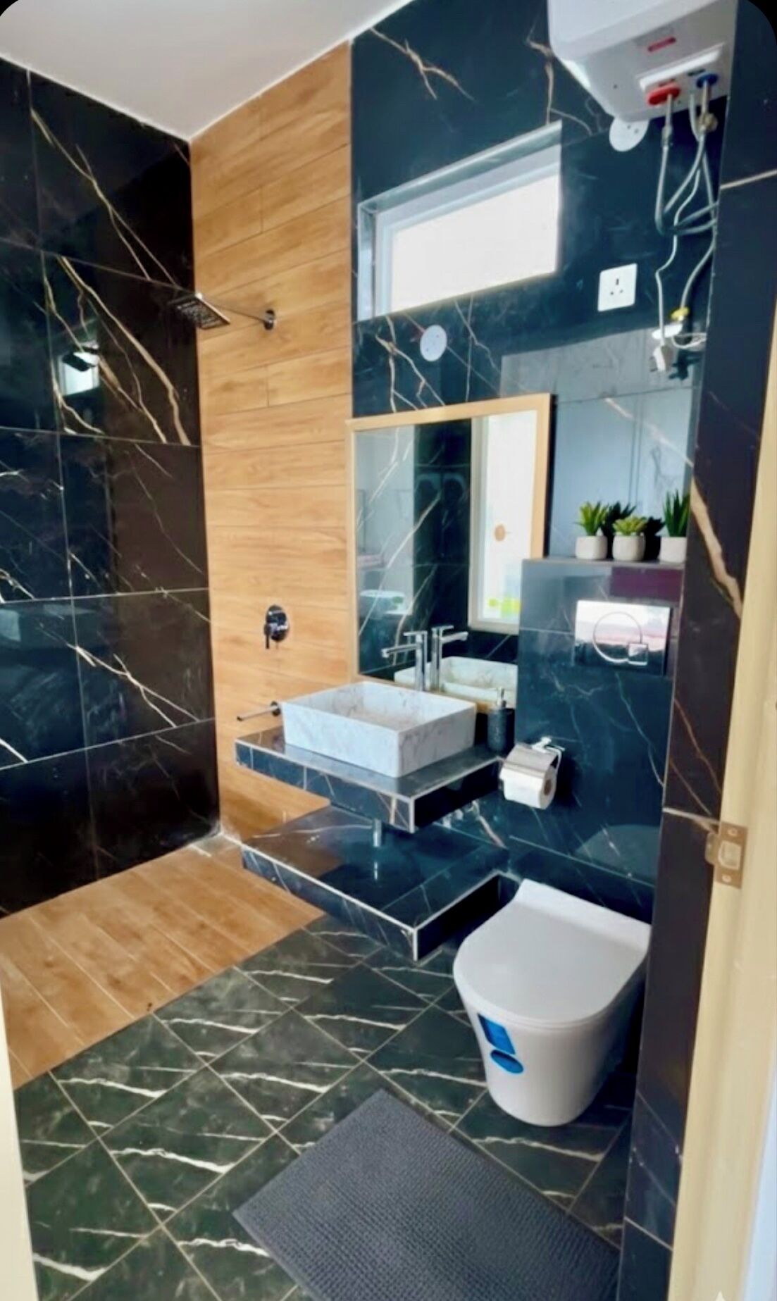 Un baño moderno con un espejo grande, un lavabo y un inodoro.