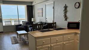 A compact living space with a kitchenette, a dining area, and a view of the sea. - Oceanfront 1-bedroom condo with spectacular sunrises Pool Gym Jacuzzi Sauna 🏖️ (Daytona Beach)