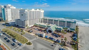 A coastal hotel with multiple buildings, a parking lot, and a beach view. - Oceanfront 1-bedroom condo with spectacular sunrises Pool Gym Jacuzzi Sauna 🏖️ (Daytona Beach)