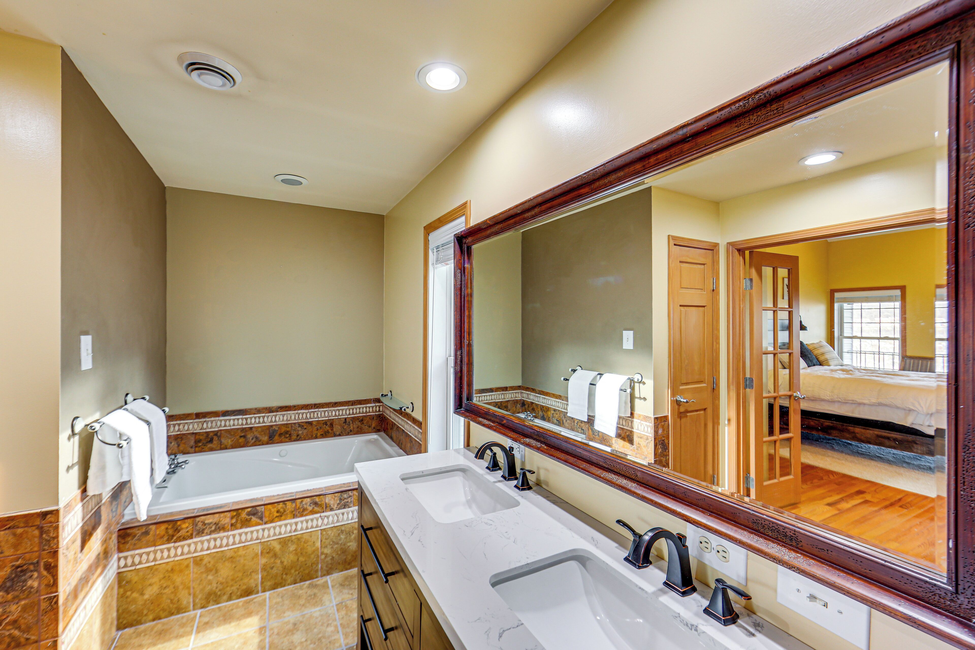A bathroom with two sinks, a large mirror, and a bathtub.