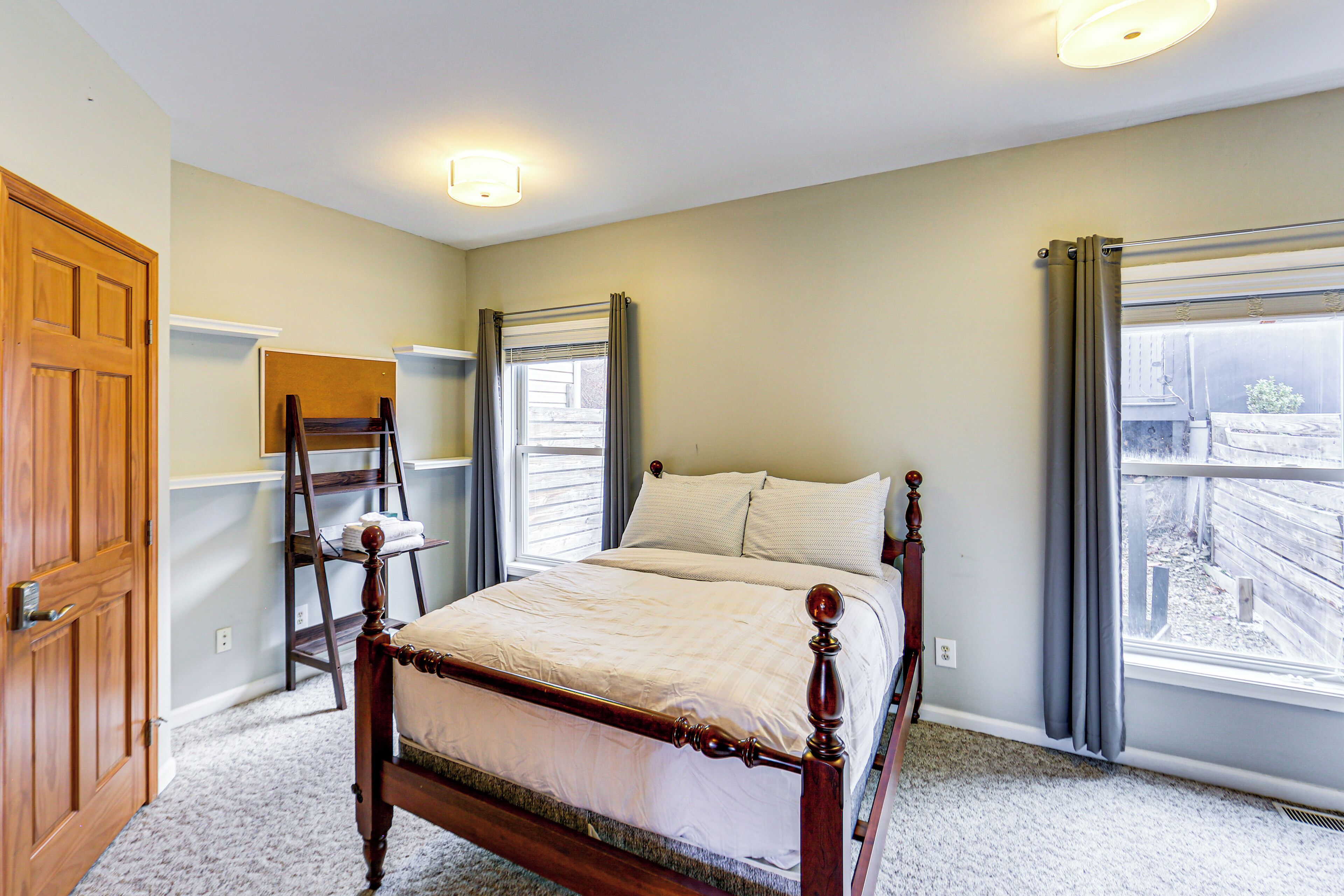 A bedroom with a wooden bed, a ladder, and a window with curtains.