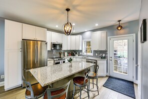 A modern kitchen with a stainless steel refrigerator, granite countertop, and bar stools. - 2 Mi to Market Sq! Row House w/ Dedicated Office (Pittsburgh)