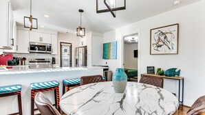 A modern kitchen with white cabinets, stainless steel appliances, and a marble island with seating. - Fenced Backyard! West ATL Home Near Mercedes-benz (Atlanta)