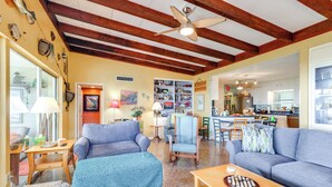 A spacious living room with a high ceiling, wooden beams, and a large window. - Lake Harris Retreat: 2 Docks & Kayaks! (Leesburg)
