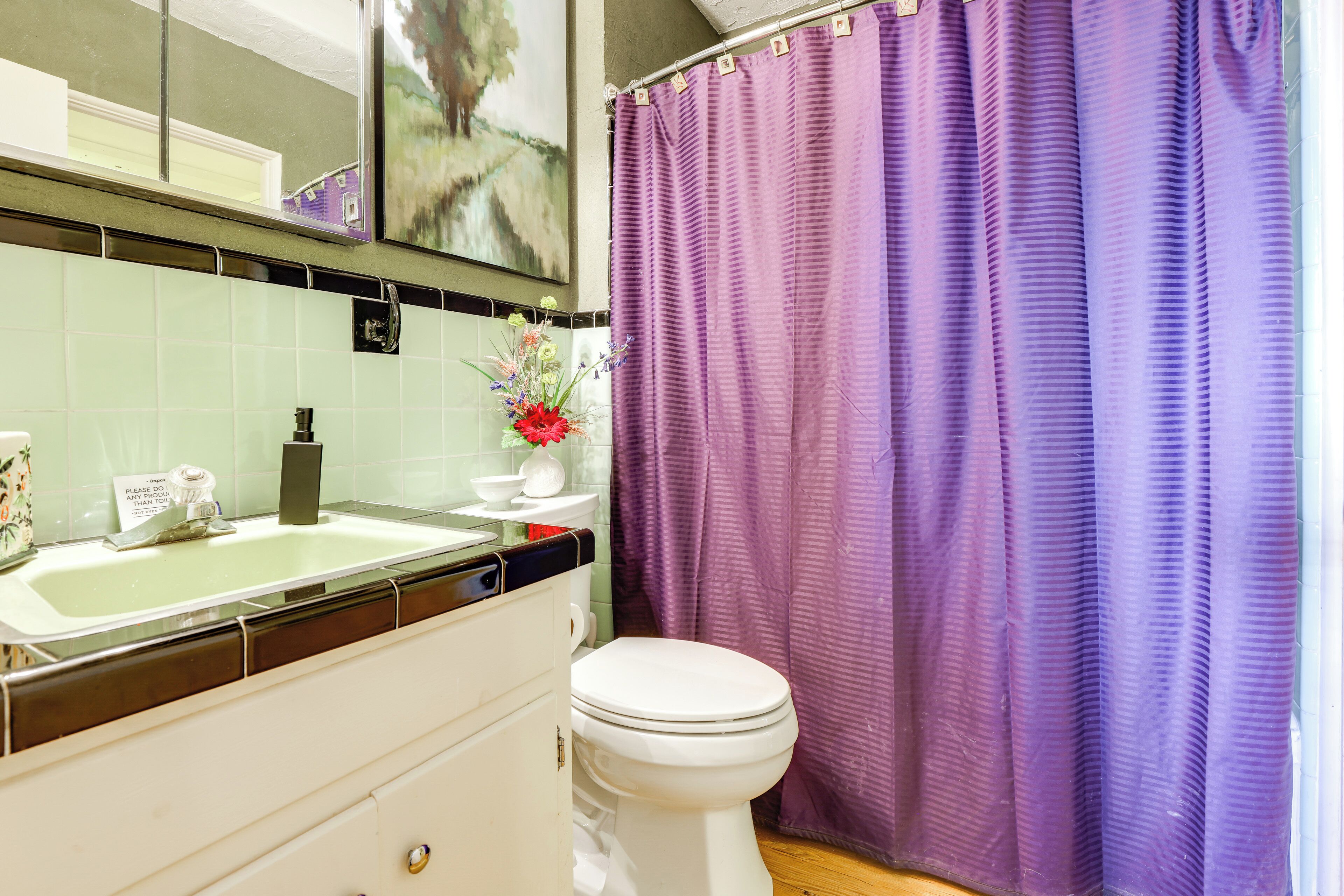 A bathroom with a white sink, a toilet, and a purple shower curtain.