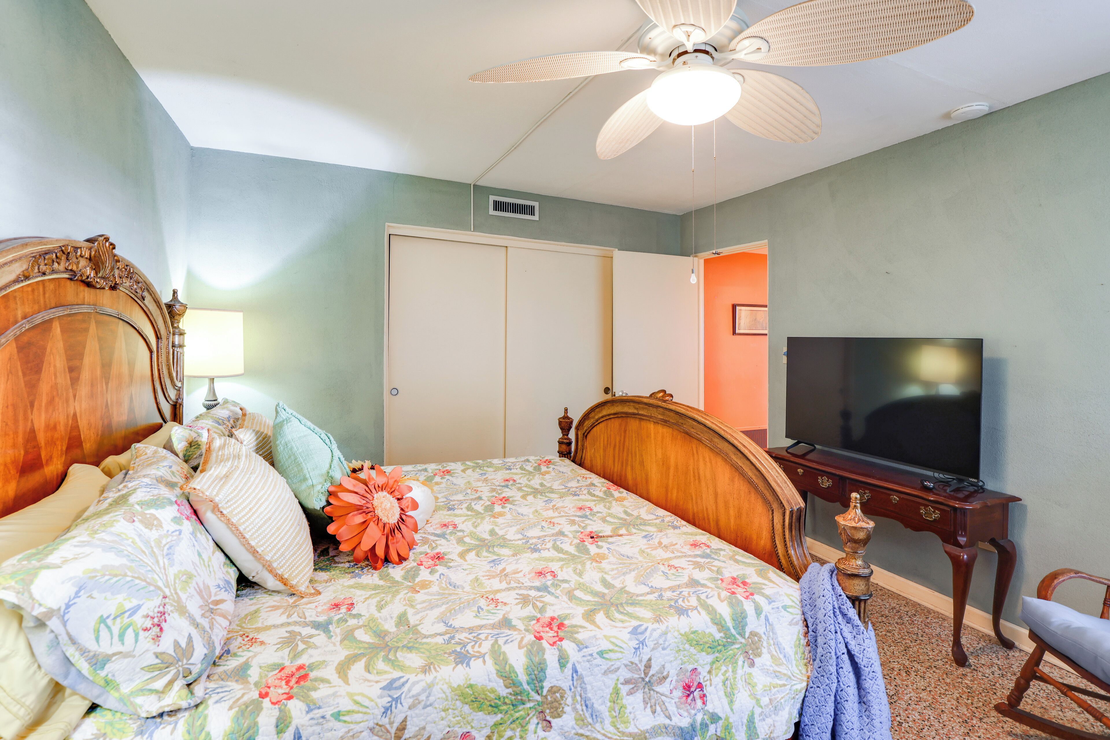 Quarto com cama, televisão, escrivaninha e cadeira.