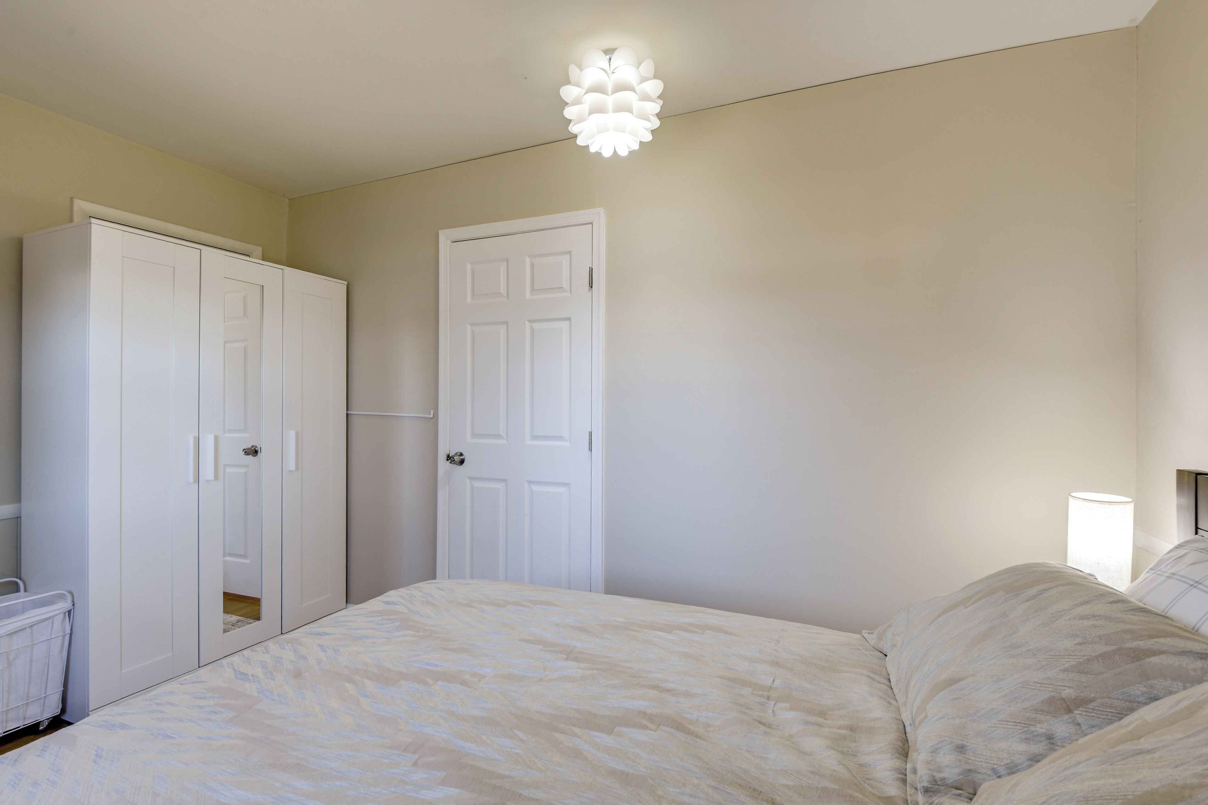 A bedroom with a bed, a wardrobe, and a door.