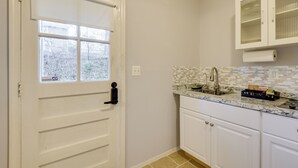 A kitchen with white cabinets, a tiled backsplash, and a window with blinds. - Convenient + Cozy! Apartment in DC Suburbs! (Silver Spring)