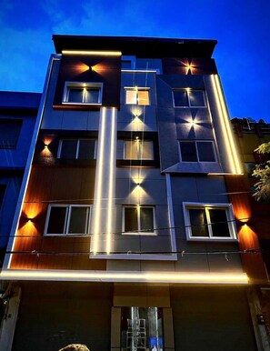 A multi-story building with a modern design, featuring a central vertical light strip and multiple illuminated windows. - Hotel Green view (Ujjain)