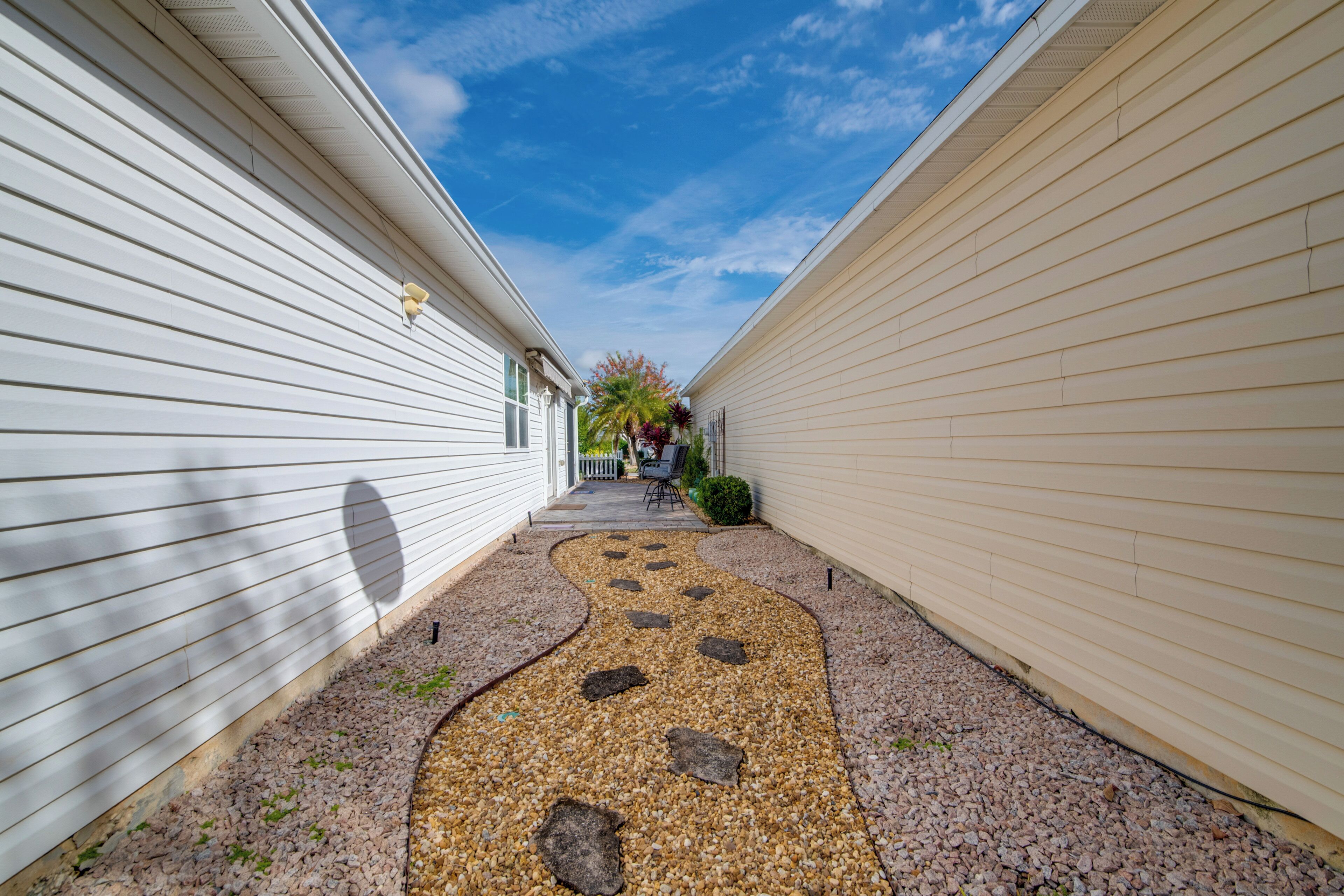 A narrow pathway with stepping stones leading to a house with a white exterior.
