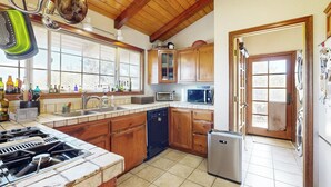 Una cocina con armarios de madera, lavavajillas, microondas y refrigerador.