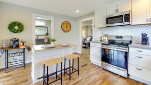Une cuisine moderne dotée d’un îlot central, d’appareils électroménagers en acier inoxydable et d’une guirlande décorative accrochée au mur.