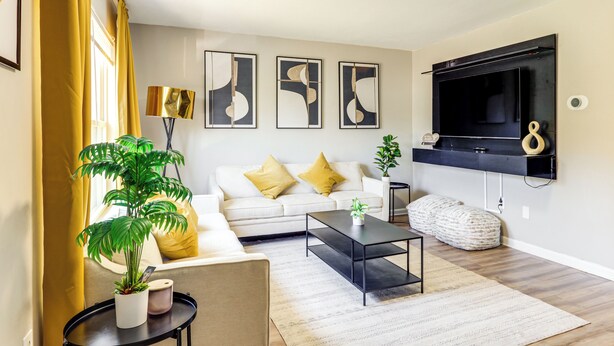 Un salon moderne avec un canapé, une table basse et un téléviseur fixé au mur.