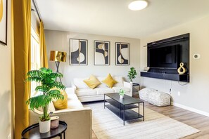 A modern living room with a sofa, coffee table, and a TV mounted on the wall. - 6 Mi to Downtown Cincy: Group-friendly Townhome! (Cincinnati)