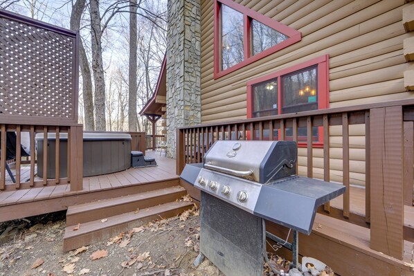 A wooden deck with a grill and hot tub, surrounded by trees. - Creek On-site! Cabin 7 Mi to Cataloochee Ski Area (Maggie Valley)