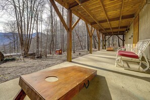 A covered outdoor area with a wooden table, a rocking chair, and a bench. - Family Log Cabin w/ Mtn Views, 2 Mi to Tube World! (Maggie Valley)