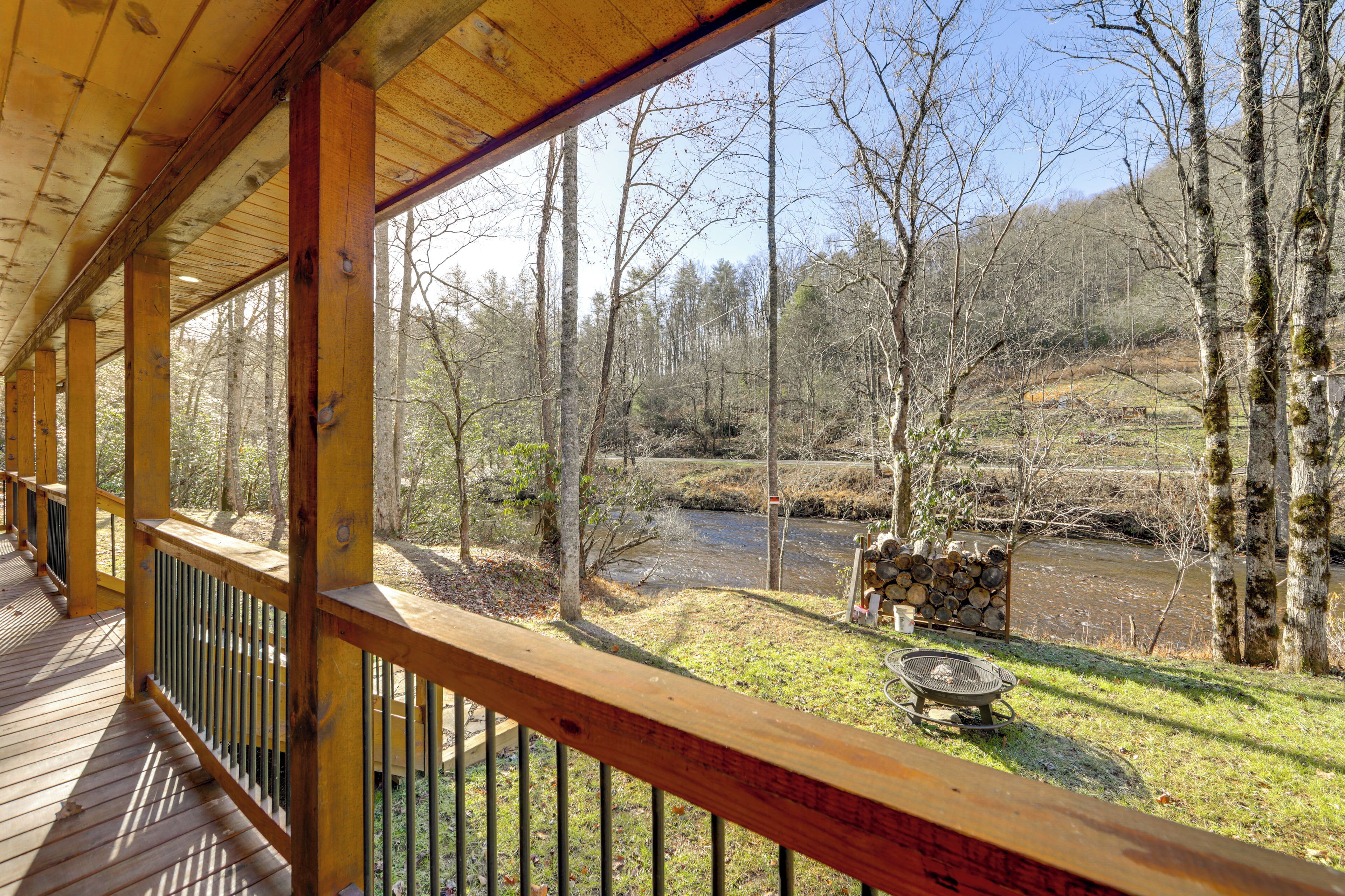 Une terrasse en bois avec une rambarde donnant sur une rivière et une zone boisée.