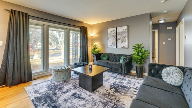 A modern living room with a grey sofa, a black coffee table, and a patterned rug. - Game, Stay & Play: Family Home in Westland! (Westland)