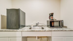 Une cuisine équipée d’un réfrigérateur, d’une machine à café et d’un four à micro-ondes, le tout posé sur le plan de travail.