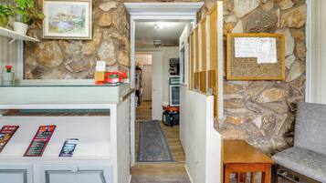 A stone-walled hallway with a reception desk, a framed welcome sign, and a grey sofa.