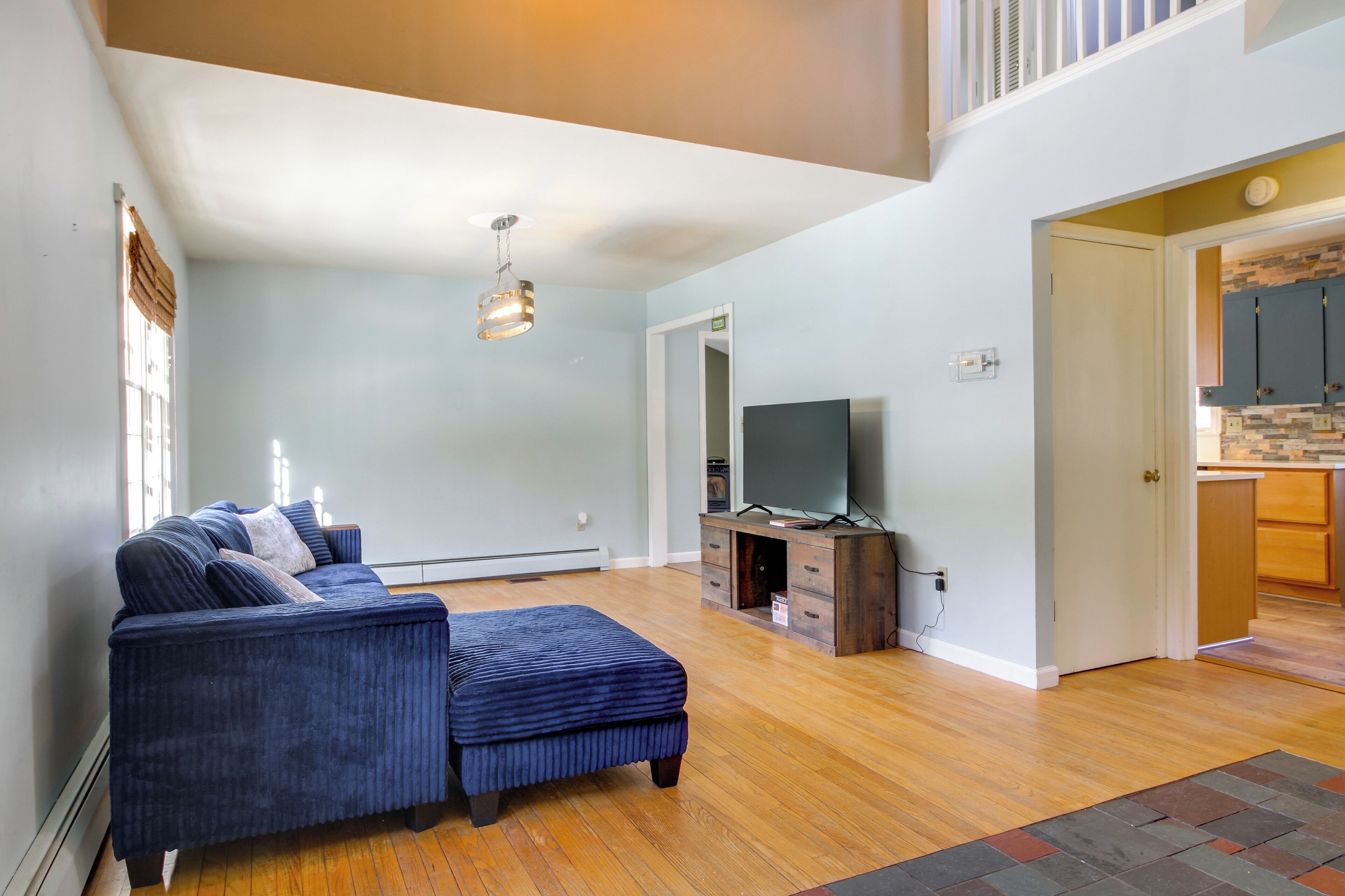 A living room with a blue sofa, a television, and wooden flooring.