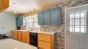 A modern kitchen with wooden cabinets, a dishwasher, and a large island. - Hiking & Skiing Galore! Home in East Wallingford (East Wallingford)