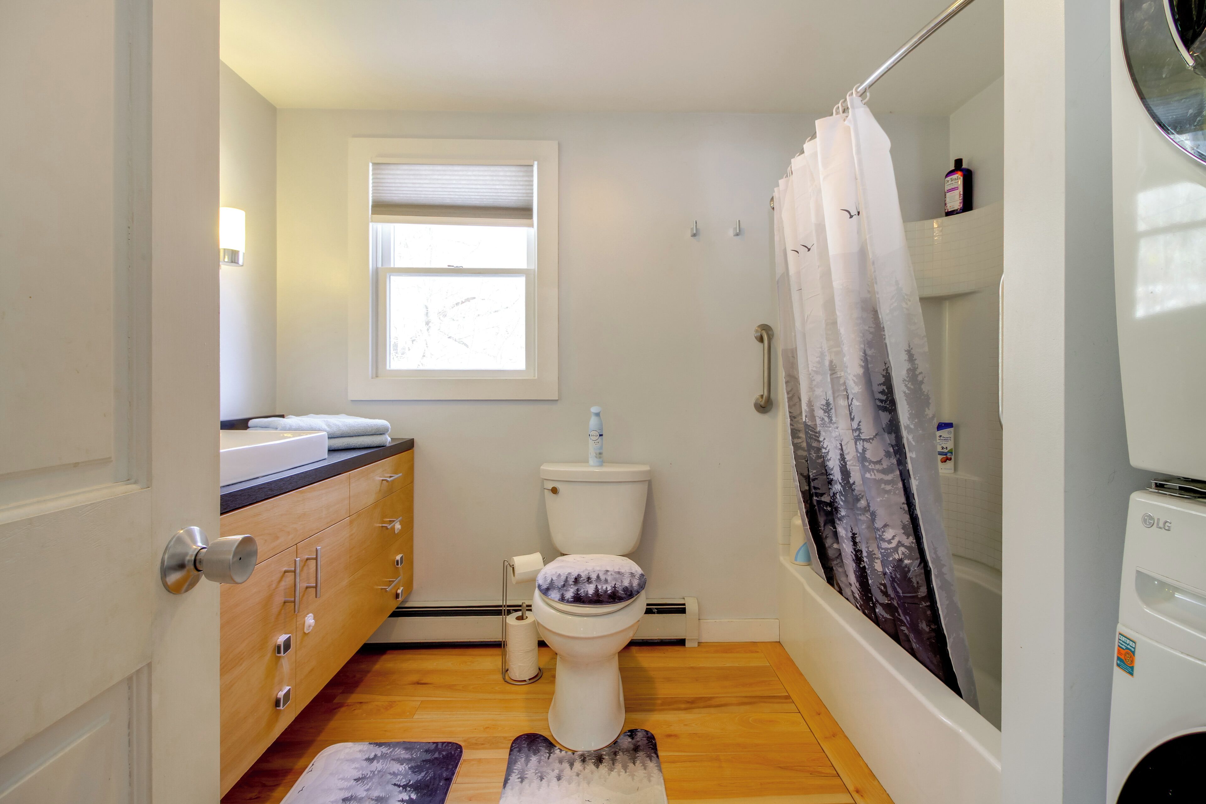 A bathroom with a toilet, a sink, a shower, and a window.