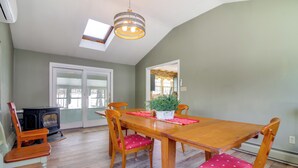 A dining area with a wooden table and chairs, a potted plant, and a wood-burning stove. - Hiking & Skiing Galore! Home in East Wallingford (East Wallingford)