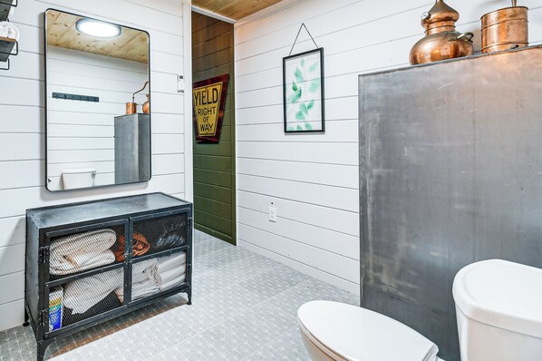 A bathroom with a white toilet, a large mirror, and a metal cabinet.